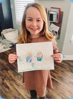 A girl holding up her drawing