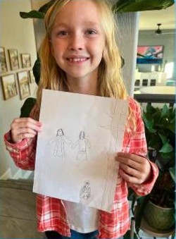 A girl holding up her drawing