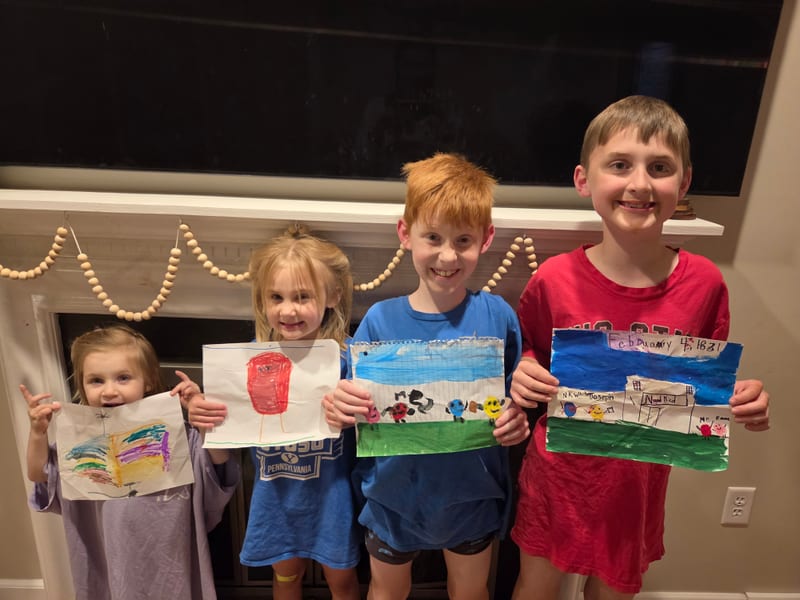 Four kids holding up their drawings