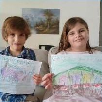 Two children holding up their drawings