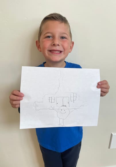 A boy holding up his drawing