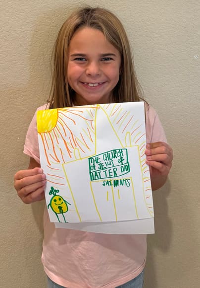 A girl holding up her colorful drawing