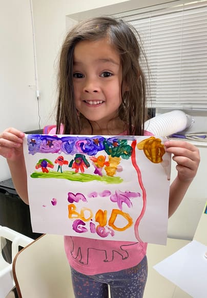 A child holding up a colorful drawing