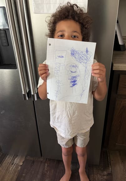 A boy holding up his drawing