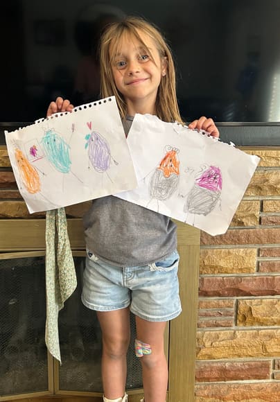 A girl holding up two drawings