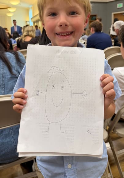 A boy holding up his drawing