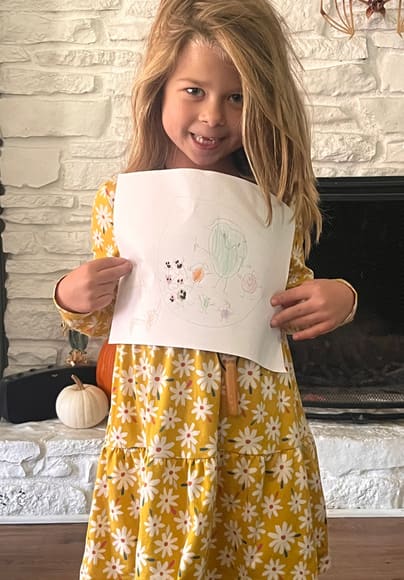 A girl holding up her drawing