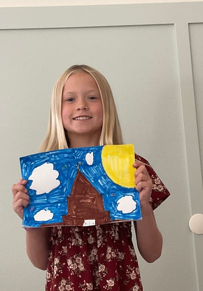 A girl holding up her painting